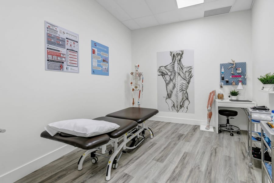 A treatment room at the clinic, with a plinth, an anatomical skeleton and a back muscle chart