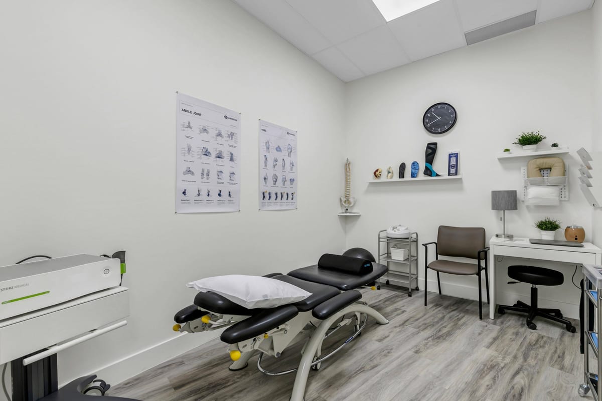 A physiotherapy treatment room at the clinic, with a treatment plinth, joint charts and a laser unit